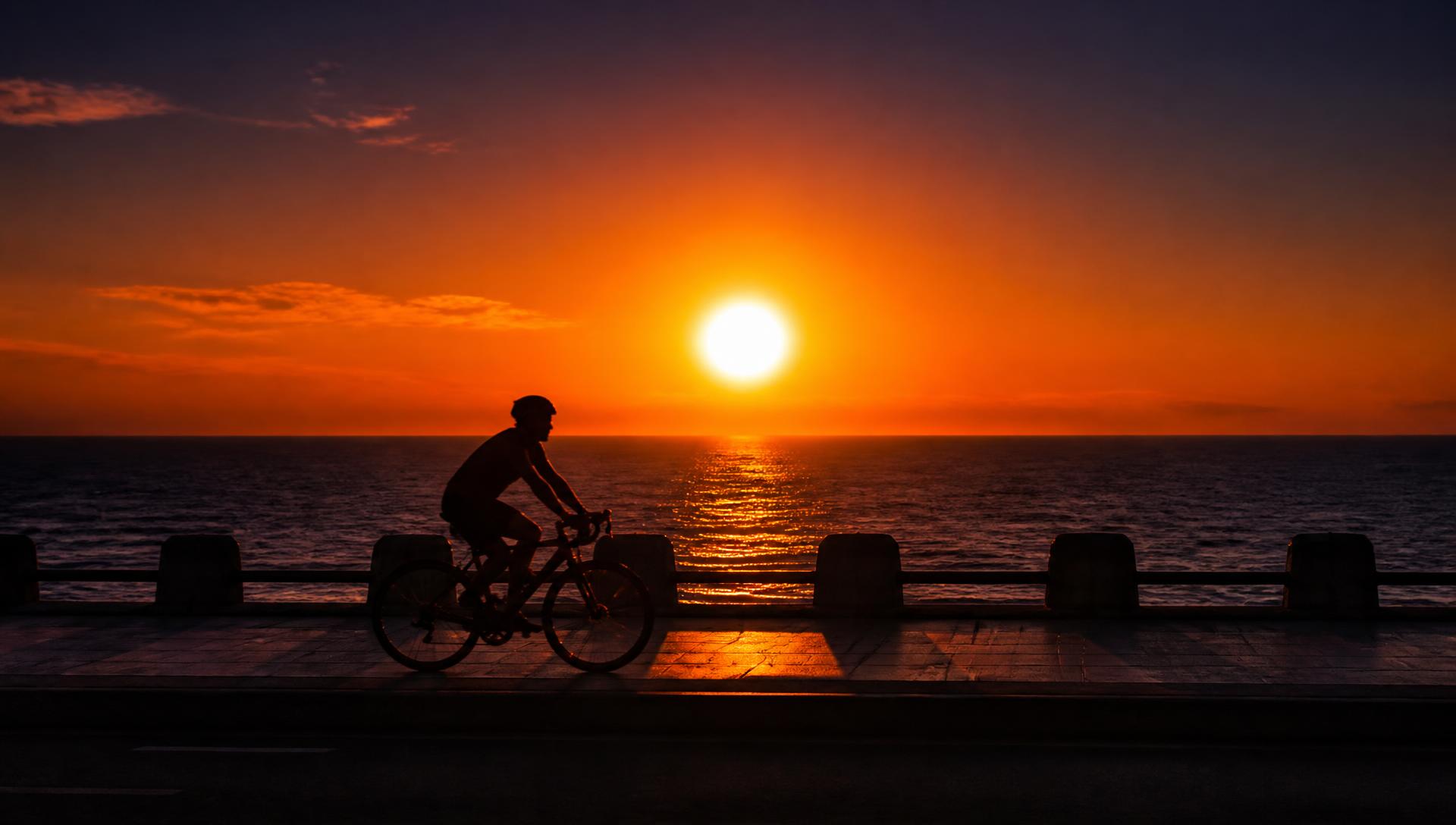 A cyclist silhouetted against the sunset over the Arabian Sea